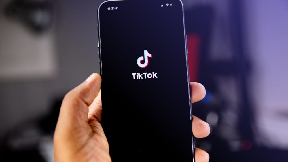 Close-up image of hand holding a smartphone with TikTok app