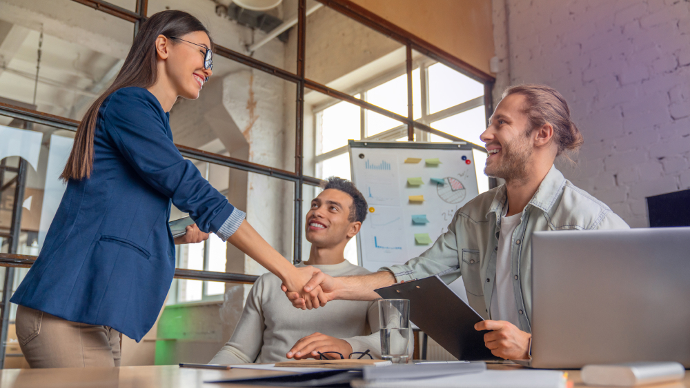 Businesswoman shaking hands with client in a meeting room.
