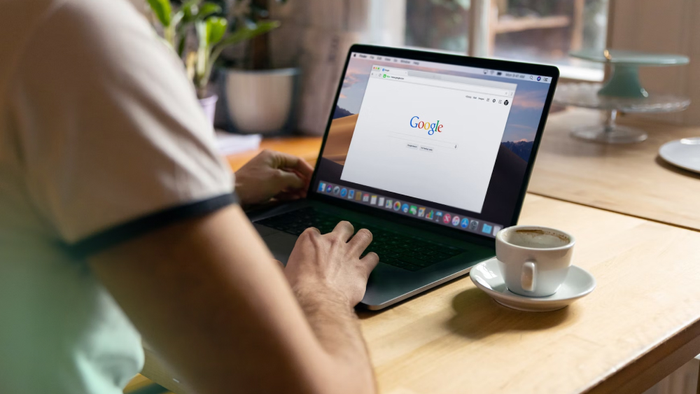 Person typing on laptop with Google search engine on screen